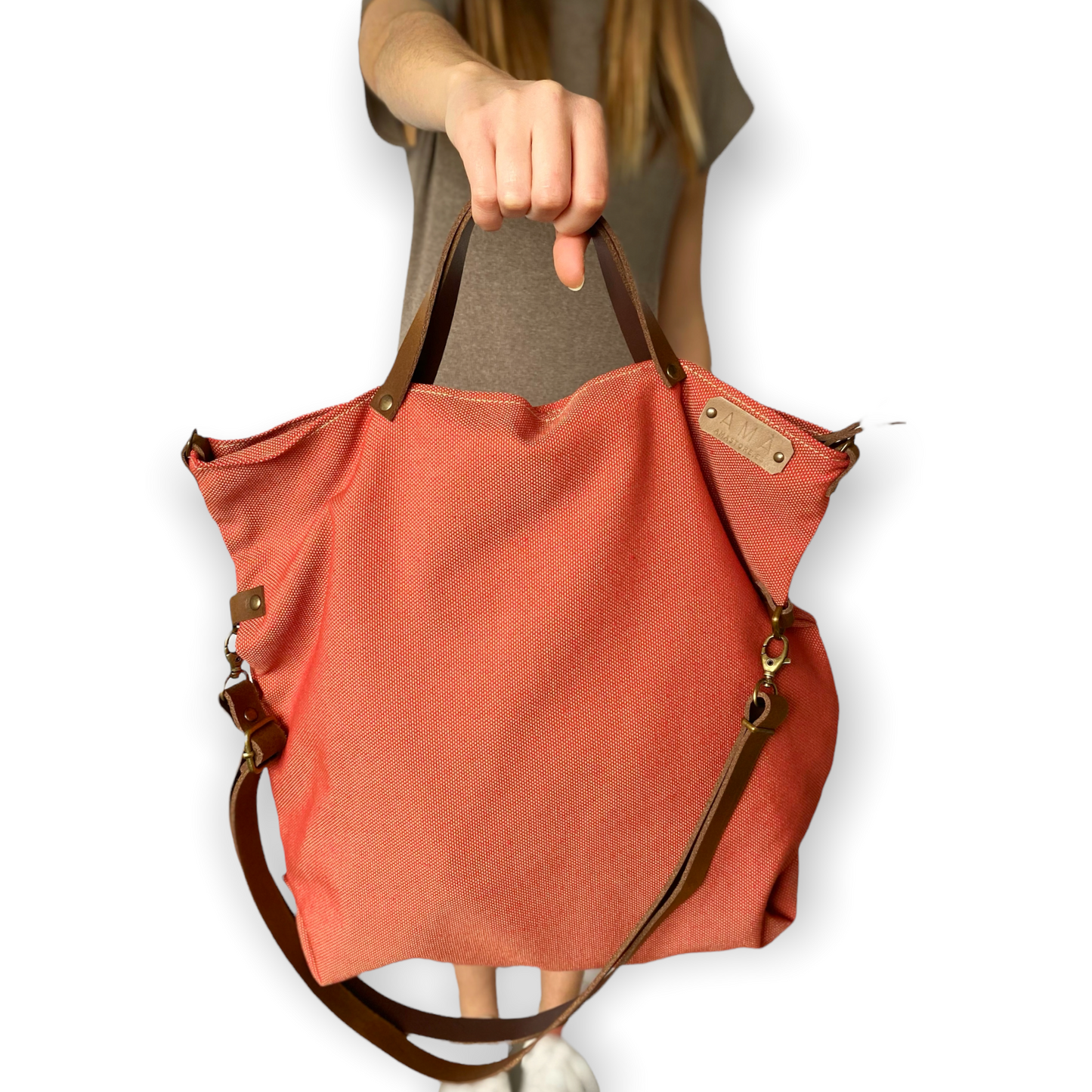 Bolso hecho a mano de loneta color teja antimanchas con forro y bolsillo interior. Un modelo super cómodo y funcional porque lo puedes llevar de mano, tipo bandolera o colgado al hombro. Las asas son de cuero regulable color marrón con mosquetones que puedes ponerlo a 2 alturas según la capacidad que necesites del bolso. Cierre con cremallera.