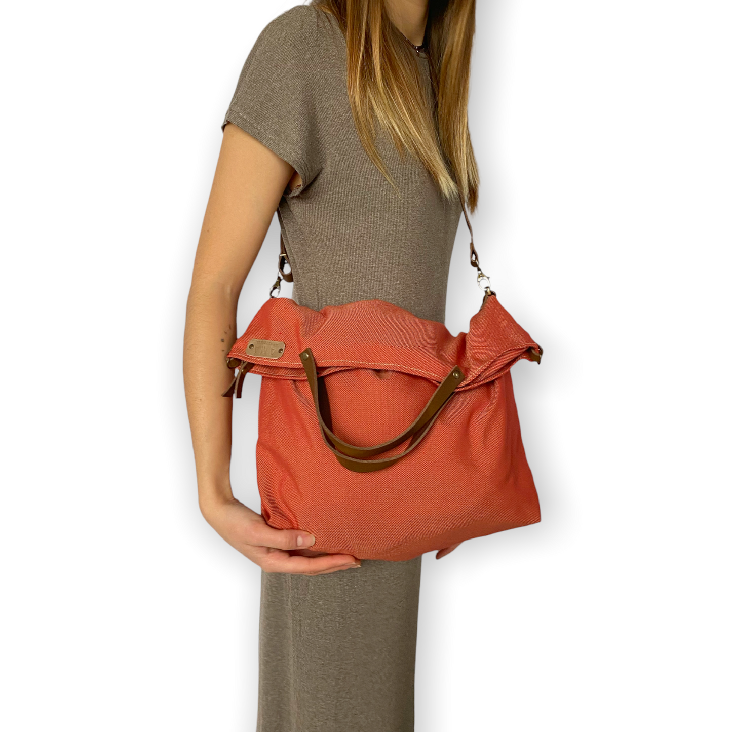 Bolso hecho a mano de loneta color teja antimanchas con forro y bolsillo interior. Un modelo super cómodo y funcional porque lo puedes llevar de mano, tipo bandolera o colgado al hombro. Las asas son de cuero regulable color marrón con mosquetones que puedes ponerlo a 2 alturas según la capacidad que necesites del bolso. Cierre con cremallera.