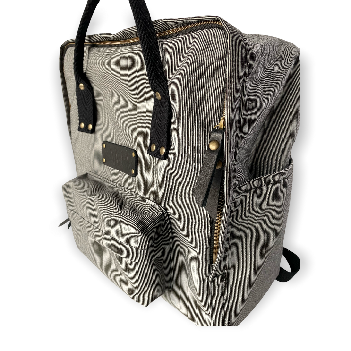 La mochila Alexa está hecha con tejido impermeable de rayas muy finas negras y blancas y con dos cintas negras en cinta de algodón regulables. En la parte superior tiene dos asas con un botón para proteger mejor su contenido. También tiene un bolsillo delantero donde podrás guardar las cosas para tenerlas más a mano y un bolsillo a cada lado para que puedas guardar el paraguas, la botella de agua…