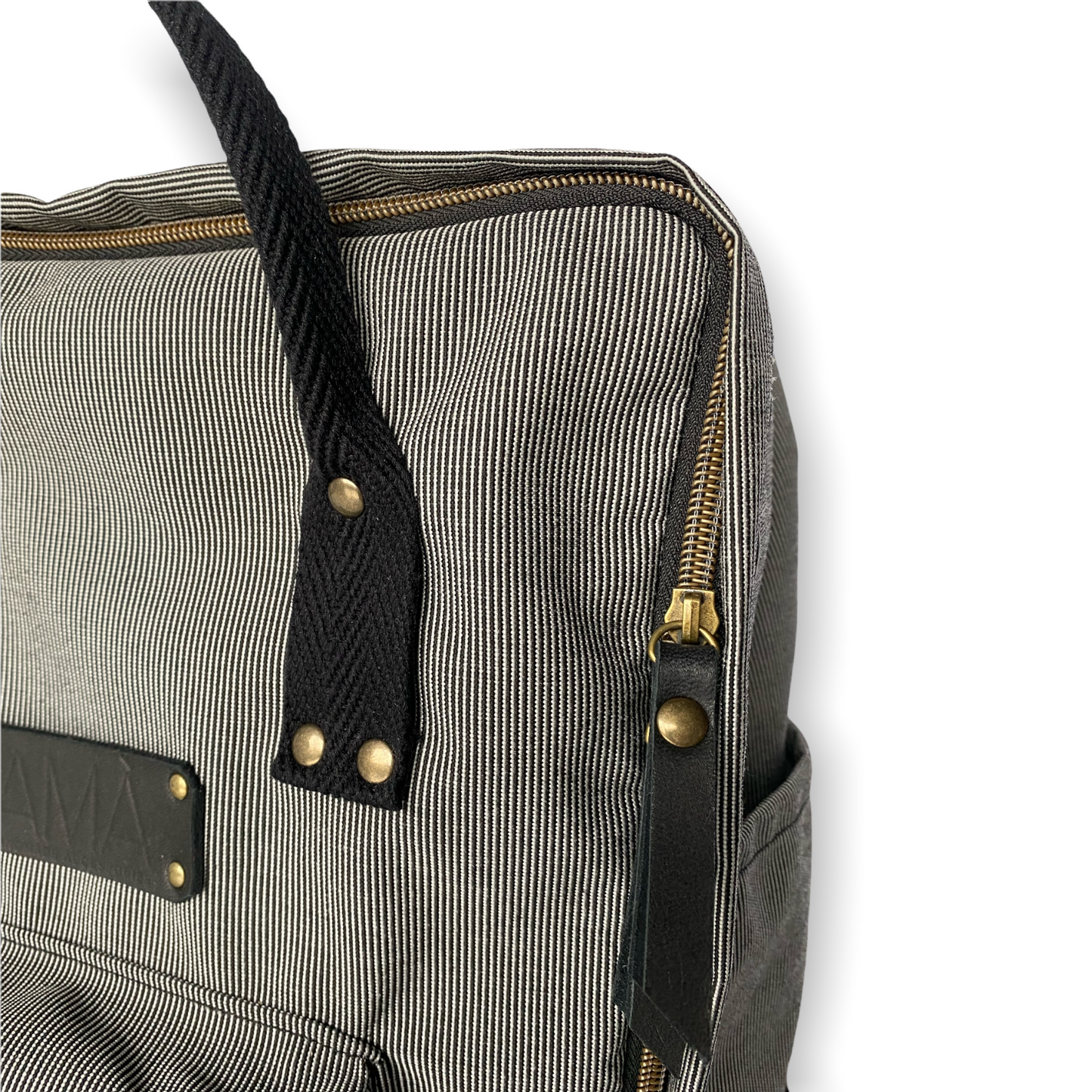 La mochila Alexa está hecha con tejido impermeable de rayas muy finas negras y blancas y con dos cintas negras en cinta de algodón regulables. En la parte superior tiene dos asas con un botón para proteger mejor su contenido. También tiene un bolsillo delantero donde podrás guardar las cosas para tenerlas más a mano y un bolsillo a cada lado para que puedas guardar el paraguas, la botella de agua…