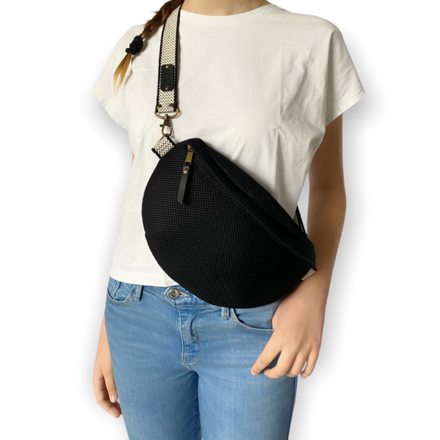 Esta práctica riñonera te ayudará a llevar lo preciso y necesario. Realizada con tejido tipo neopreno color negro con efecto nido de abeja. Con una cremallera negra y un asa regulable de 3 cm de algodón blanco y negro jaspeado ayuda a llevarla sobre el hombro, a la cintura o cruzada sobre el pecho para evitar robos. Tiene un mosquetón para engancharlo en cualquier sitio. Bonito forro y un bolsillo para administrar el espacio.