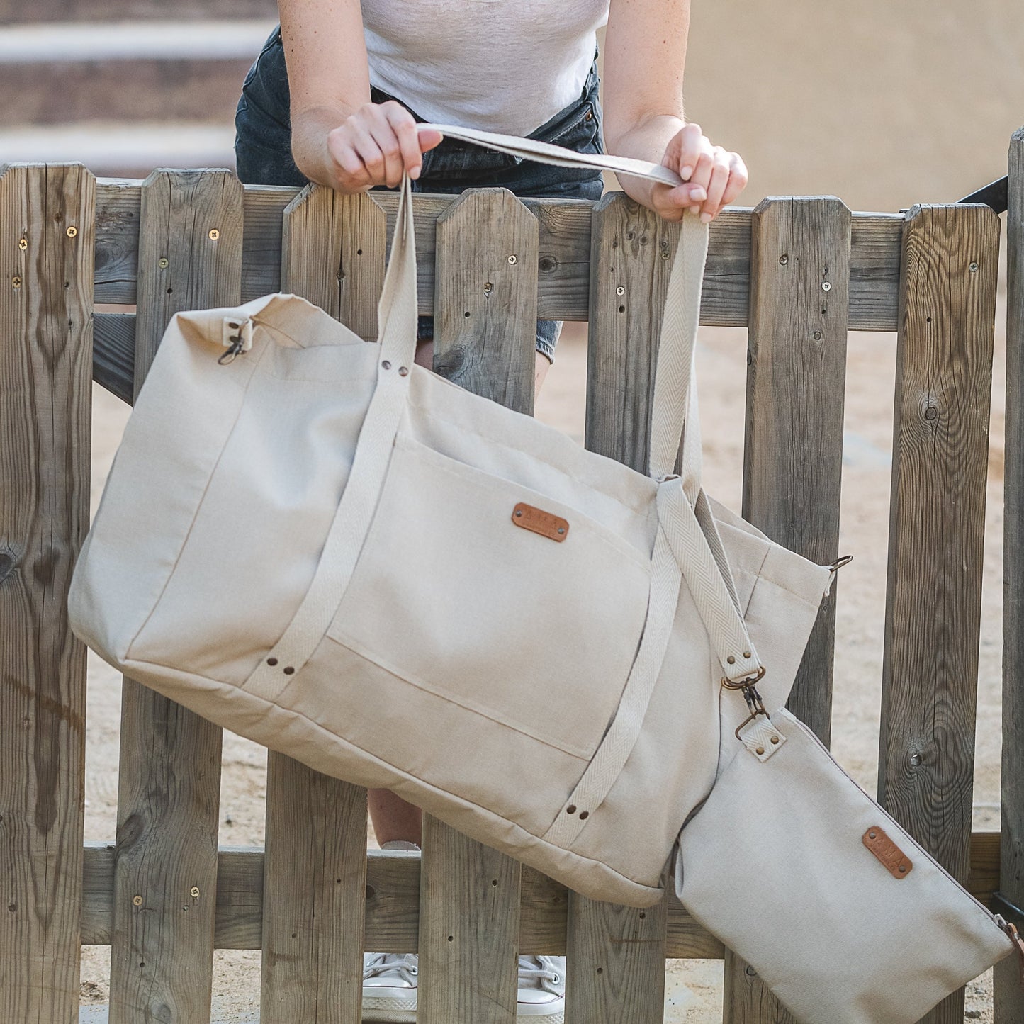 PAck de Bolsa de Playa XXL color beige hecha a mano en Barcelona con neceser a juego. Estárealizado con tejido repelente al agua y dispone de mosqueton lateral para cerrarla y que quede más pequeña. Las cintas llevan una obertura para poder llevar la esterilla, la sombrilla o el sombrero y tener las manos libres