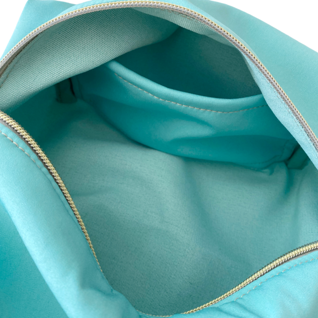 Neceser de tejido de neopreno color Aguamarina con una práctica asa de algodón color natural que te permitirá colgar el neceser del pomo de la puerta o cualquier colgador. Están realizados mano en Barcelona y disponen de forro repelente al agua y bolsillo interior. El tirador de la cremallera se convierte en un llavero extraible. Además puedes escoger personalizar tu neceser con 2 iniciales.