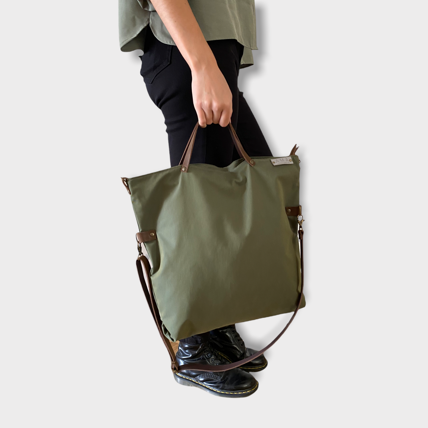 Bolso hecho a mano de tejido tipo loneta color verde militar con forro y bolsillo interior. Un modelo super cómodo y funcional porque lo puedes llevar de mano, tipo bandolera o colgado al hombro. Las asas son de cuero regulable color marrón con mosquetones que puedes ponerlo a 2 alturas según la capacidad que necesites del bolso. Cierre con cremallera. Este bolso tiene 2 opciones bandolera o Tote bag. Lleva un llavero que se puede colgar dentro de regalo para tener siempre tus llaves a mano.