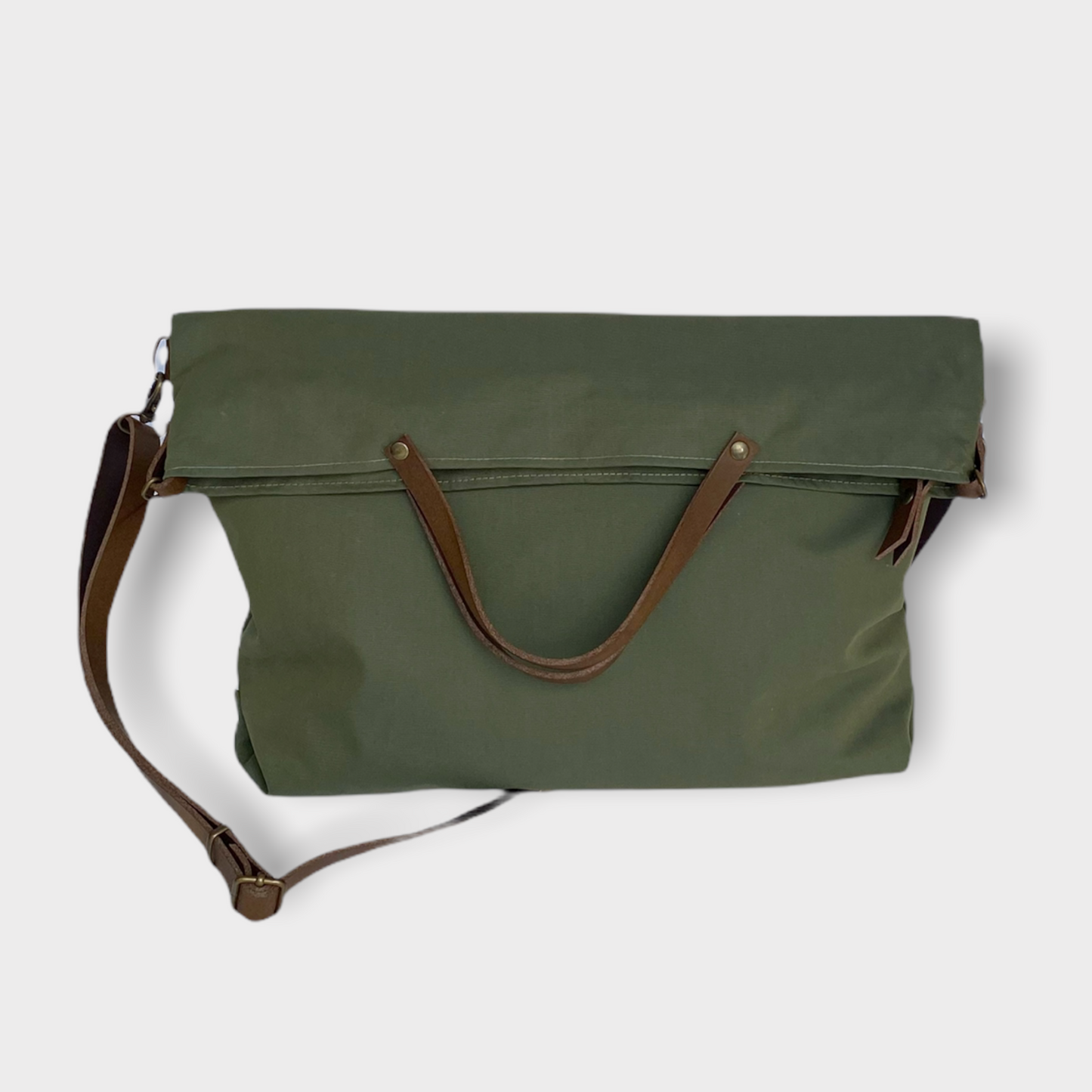 Bolso hecho a mano de tejido tipo loneta color verde militar con forro y bolsillo interior. Un modelo super cómodo y funcional porque lo puedes llevar de mano, tipo bandolera o colgado al hombro. Las asas son de cuero regulable color marrón con mosquetones que puedes ponerlo a 2 alturas según la capacidad que necesites del bolso. Cierre con cremallera. Este bolso tiene 2 opciones bandolera o Tote bag. Lleva un llavero que se puede colgar dentro de regalo para tener siempre tus llaves a mano.