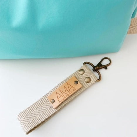 Neceser de tejido de neopreno color Aguamarina con una práctica asa de algodón color natural que te permitirá colgar el neceser del pomo de la puerta o cualquier colgador. Están realizados mano en Barcelona y disponen de forro repelente al agua y bolsillo interior. El tirador de la cremallera se convierte en un llavero extraible. Además puedes escoger personalizar tu neceser con 2 iniciales.